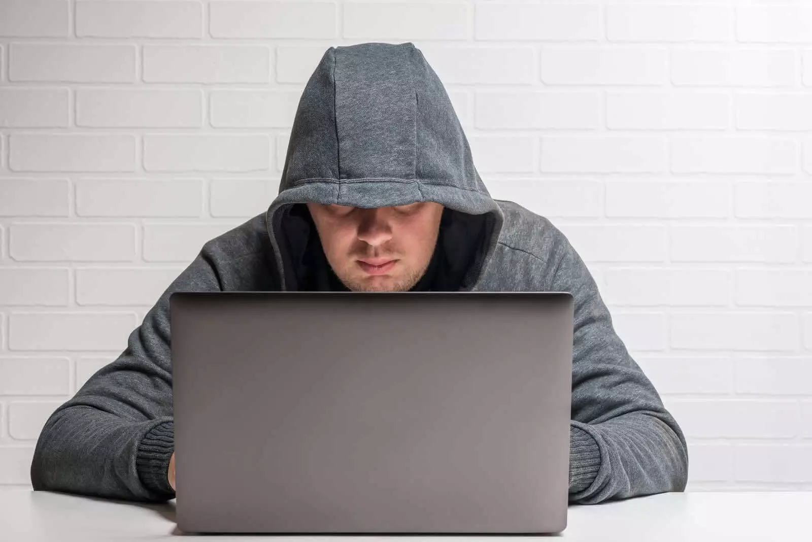 A Man In A Hoodie Is Using A Laptop To Blog Anonymously.