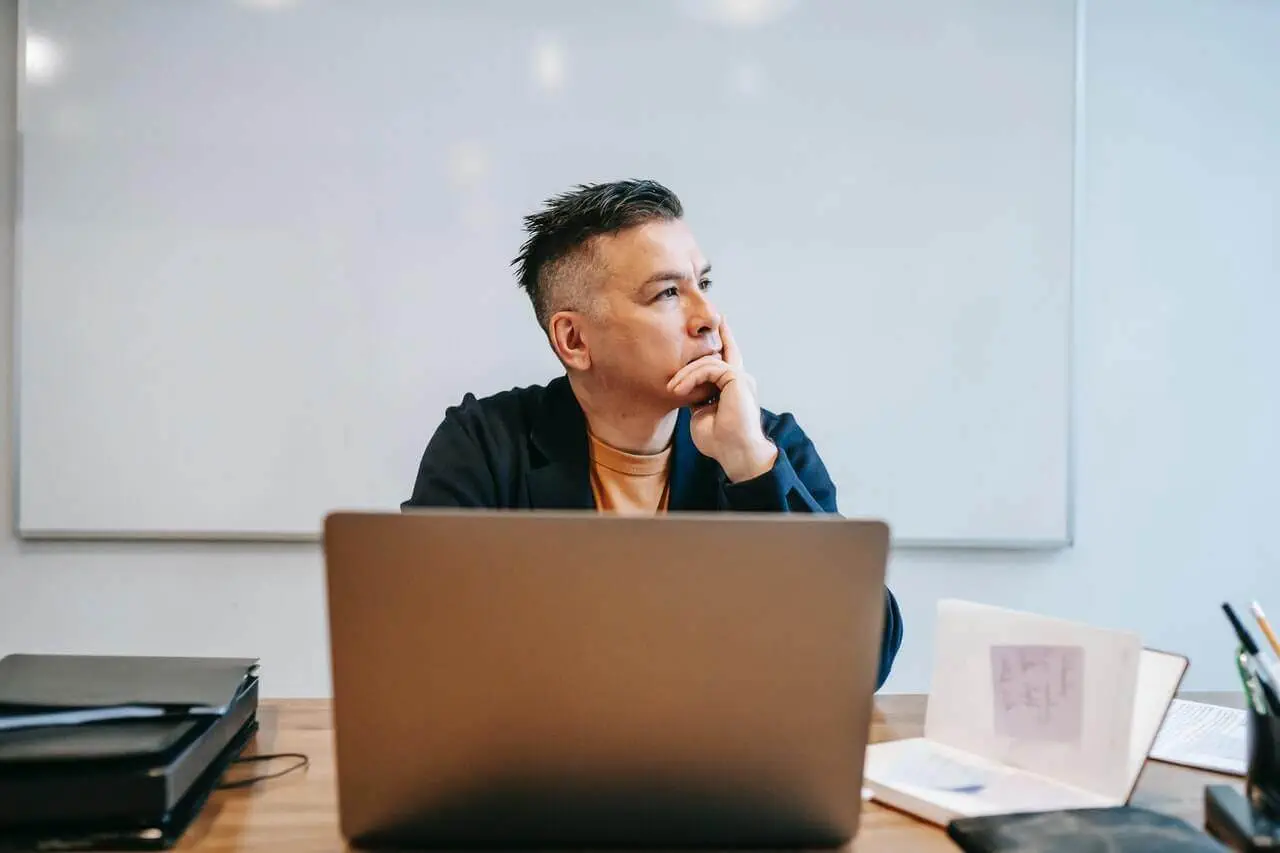 A Man Sitting At A Desk With A Laptop, Following The Ultimate Guide To Blogging For Profit.