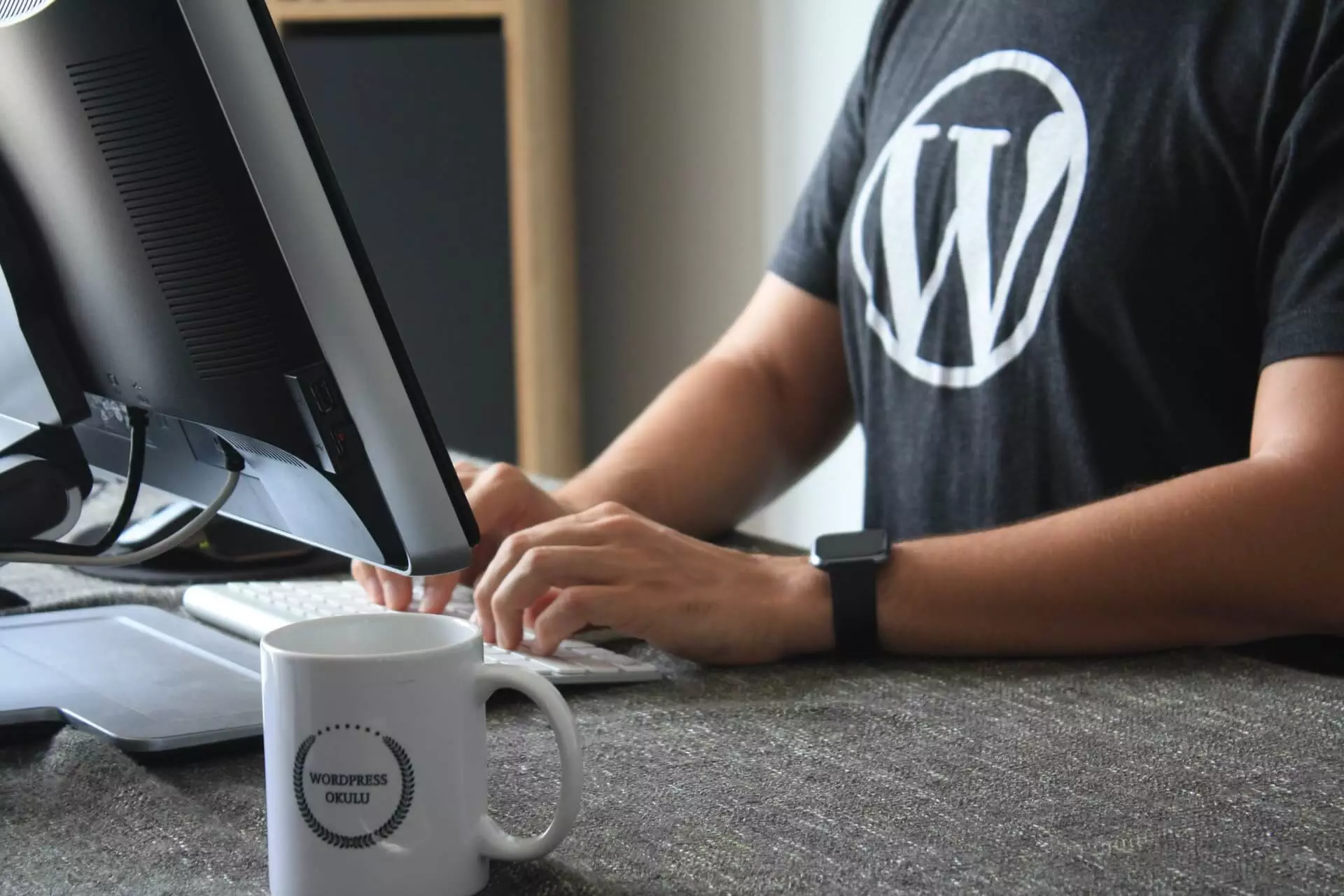 A Man Typing On A Computer With The Wordpress Logo.