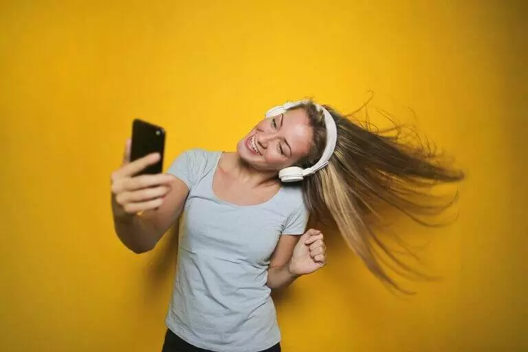 A Young Woman Is Taking A Selfie Against A Yellow Background, Showcasing The Best Ways To Make Money For Free Online.